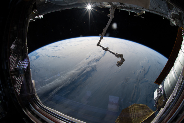 selfie of astronaut, reflection in UV shield of cloud cover earth at horizon and canada arm