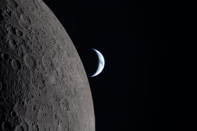 A crescent Earth sets against a grey, cratered Moon dominating the foreground|640x427